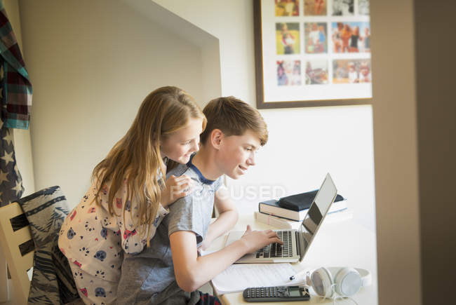 Sorella guardando fratello utilizzando laptop in camera da letto — Foto stock