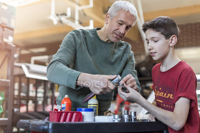 Батько навчає сина, як використовувати інструменти в авторемонтному магазині — стокове фото