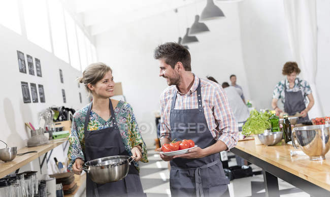 Couple carrying food in cooking class kitchen — Stock Photo