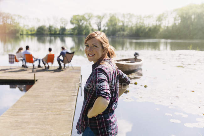 Portrait femme souriante au quai au bord du lac ensoleillé — Photo de stock