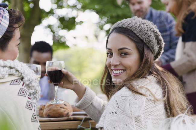 Портрет усміхненої жінки, що п'є вино на обід у патіо з друзями — стокове фото