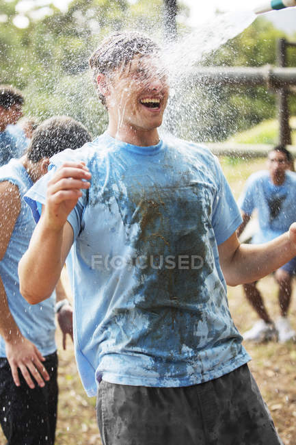 Begeisterter Mann genießt Wasserschlauch-Spray auf Bootcamp-Hindernisparcours — Stockfoto