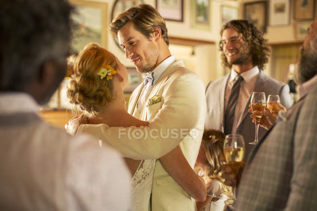 Novio abrazando novia durante la recepción de la boda en la habitación doméstica - foto de stock
