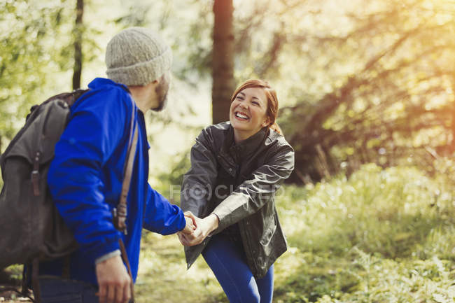 Couple souriant tenant la main randonnée dans les bois — Photo de stock