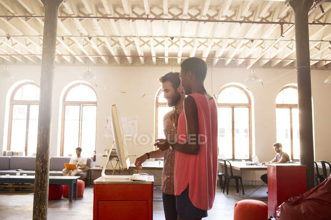 Creative business people working at computer in open office — Stock Photo