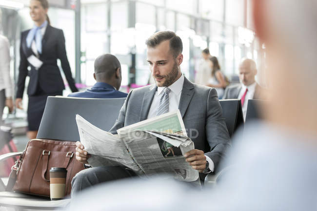 Homme d'affaires lisant un journal dans la zone de départ de l'aéroport — Photo de stock