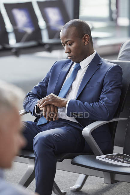 Бізнесмен перевіряє час на наручному годиннику очікування в зоні відправлення аеропорту — стокове фото