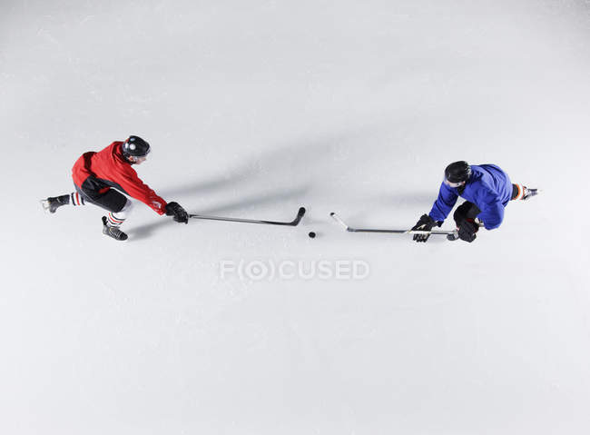 Overhead view hockey opponents going for the puck on ice — Stock Photo