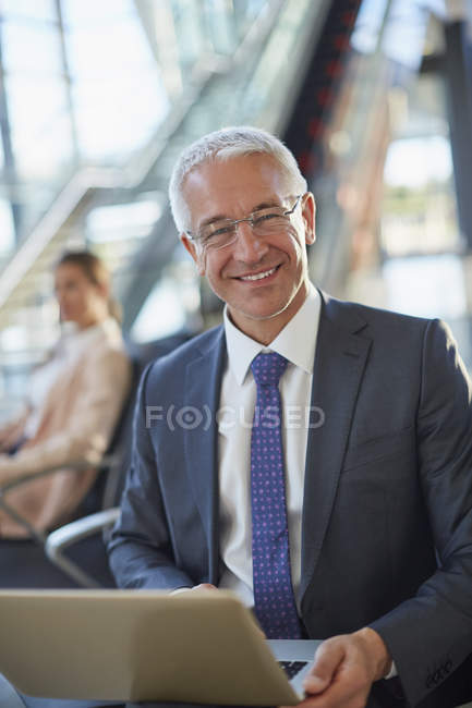 Портрет улыбающийся бизнесмен с помощью ноутбука в аэропорту — стоковое фото