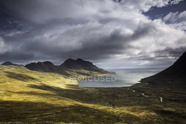 Vista del paisaje de colinas y lago de agua bajo las nubes - foto de stock