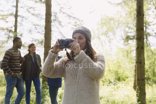Donna che utilizza macchina fotografica escursioni nel bosco — Foto stock