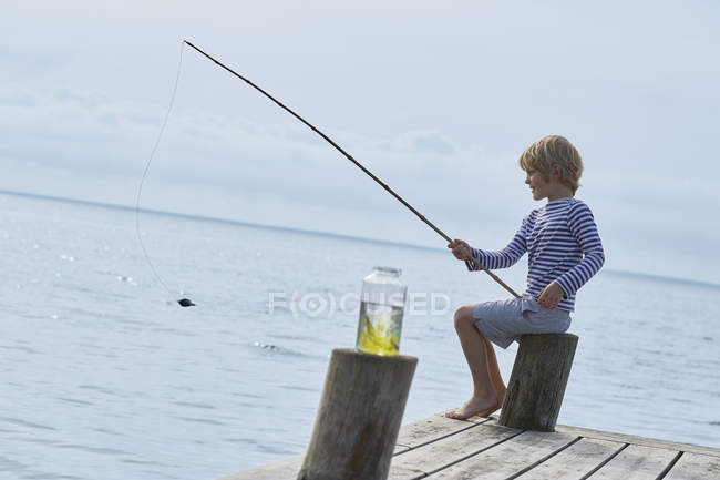 Niño pescando en el muelle del lago - foto de stock