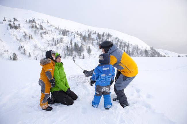 Família usando selfie stick na montanha nevada — Fotografia de Stock