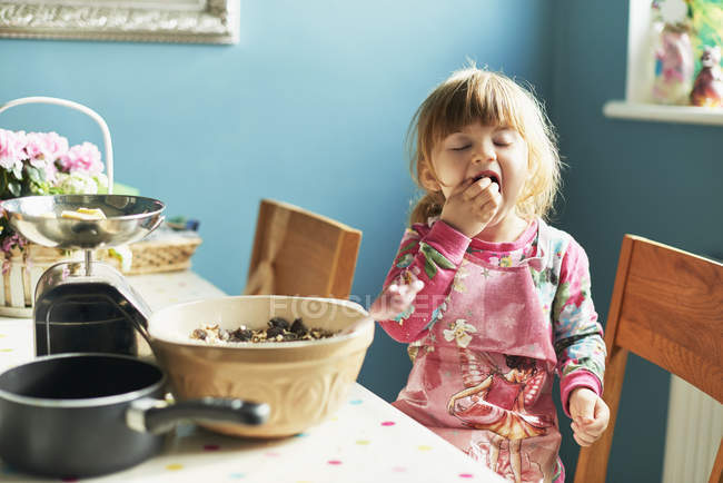 Girl tasting baking ingredients in kitchen — Stock Photo