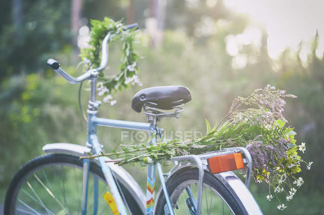Flowers and garland on bicycle in garden — Stock Photo