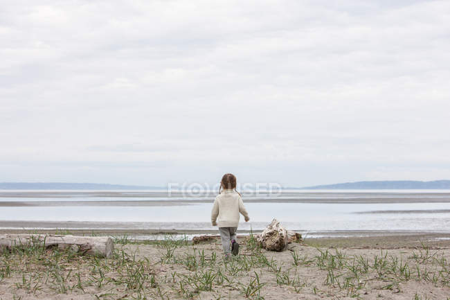 Mädchen rennt am Strand auf Ozean zu — Stockfoto