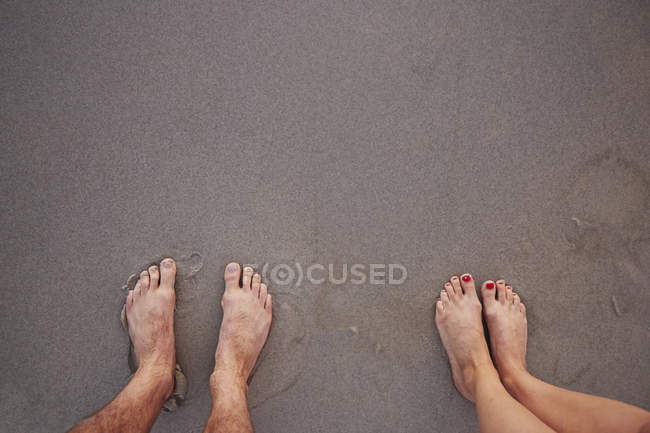 Personal perspective barefoot couple standing in wet sand on beach — Stock Photo