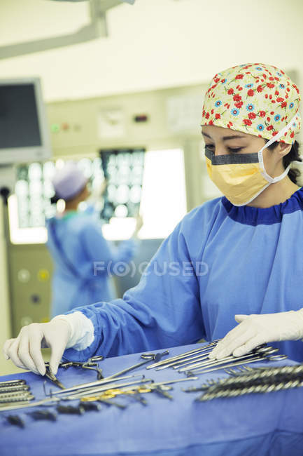 Cirurgião organizando tesoura cirúrgica na bandeja na sala de cirurgia — Fotografia de Stock