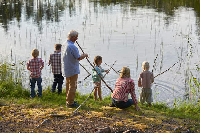 Abuelos y nietos que pescan en el lago - foto de stock