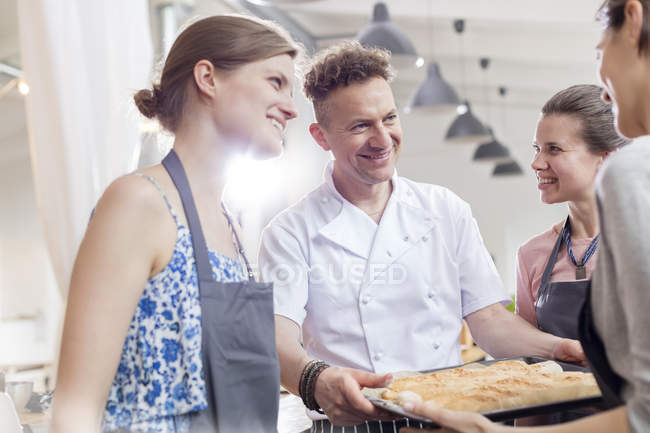 Smiling chef teacher and students in cooking class kitchen — Stock Photo