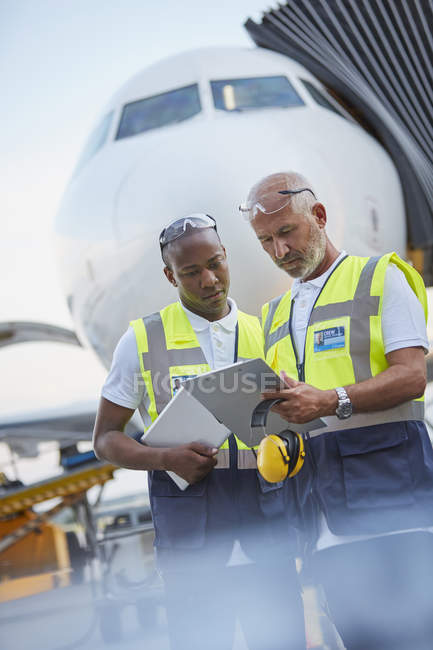 Air traffic controllers with clipboard below airplane on airport tarmac — Stock Photo