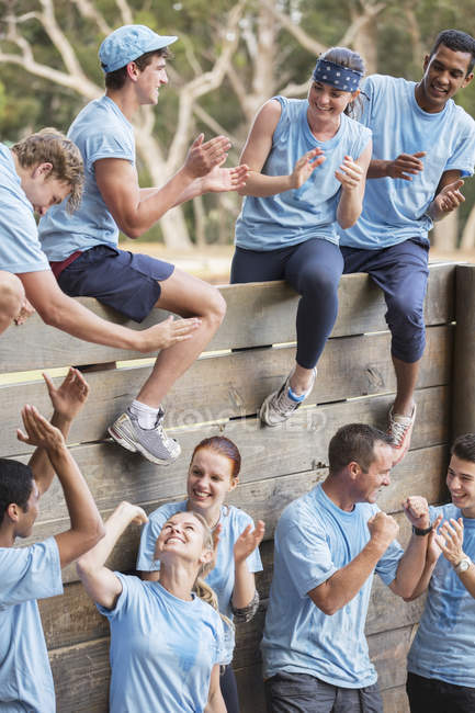 Equipe batendo palmas e comemorando na parede no campo de inicialização curso de obstáculo — Fotografia de Stock