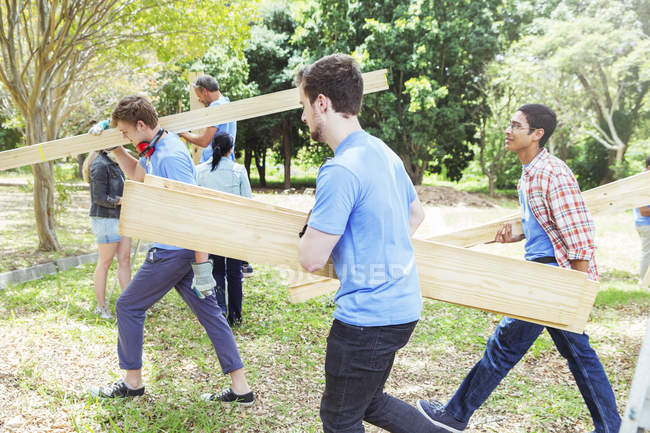 Voluntários que transportam pranchas de madeira — Fotografia de Stock