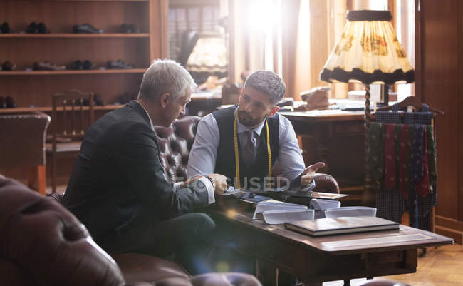 Alfaiate e empresário conversando na loja de moda masculina — Fotografia de Stock