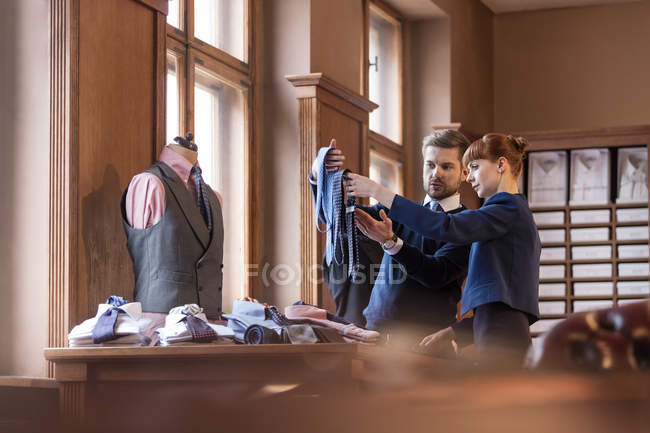 Рабочий показывает связи с бизнесменом в магазине мужской одежды — стоковое фото