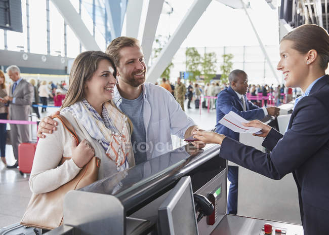 Representante de atendimento ao cliente ajudando casal no balcão de check-in do aeroporto — Fotografia de Stock