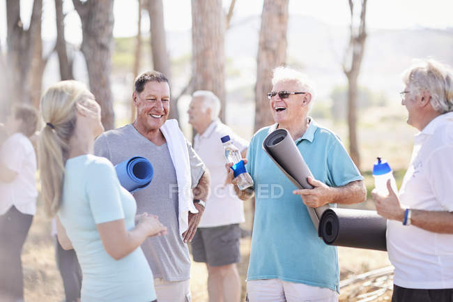 Викладач йоги розмовляти з старші чоловіки після занять в парку — стокове фото