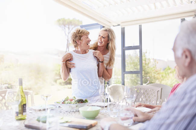 Lächelnde Tochter umarmt Seniorin beim Mittagessen auf der Terrasse — Stockfoto