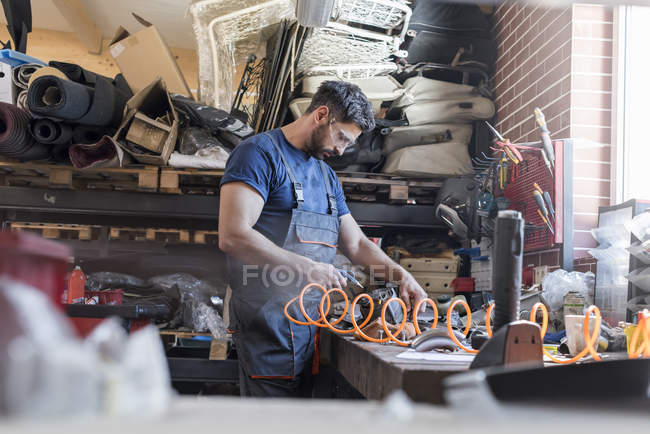 Mecânico usando equipamentos na bancada na oficina de reparação de automóveis — Fotografia de Stock