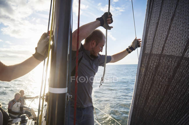 Mann passt Segeltakelage auf Segelboot an — Stockfoto