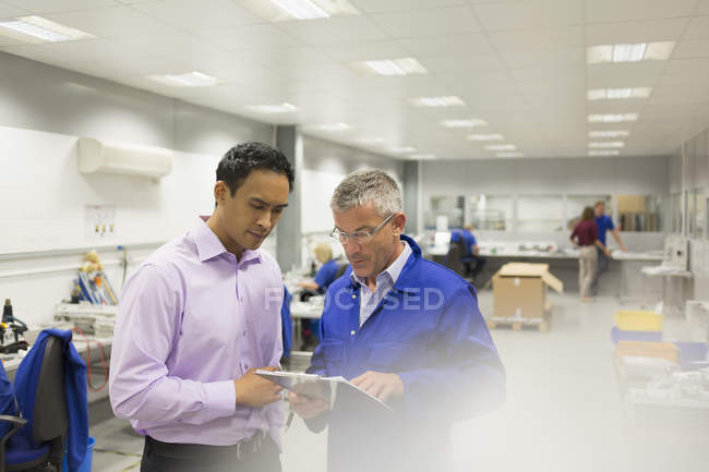 Manager and engineer looking at clipboard in steel factory office — Stock Photo