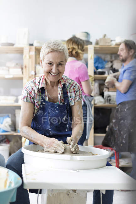 Portrait smiling senior woman using pottery wheel in studio — Stock Photo