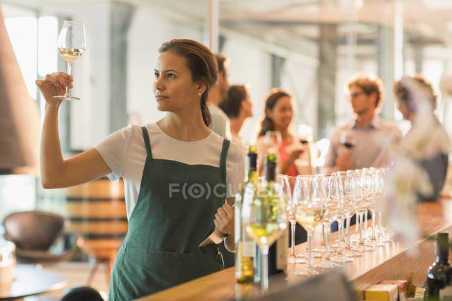 Obrero de la sala de degustación de vino examinando vino blanco - foto de stock