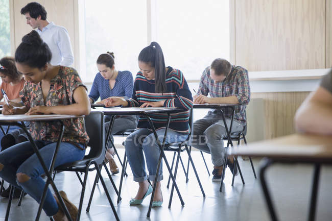 Studenti universitari che fanno test alle scrivanie in classe — Foto stock