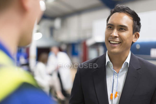 Усміхнений менеджер розмовляє з працівником на металургійному заводі — стокове фото