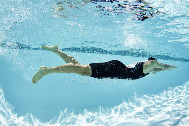 Male swimmer athlete swimming underwater in swimming pool — Stock Photo