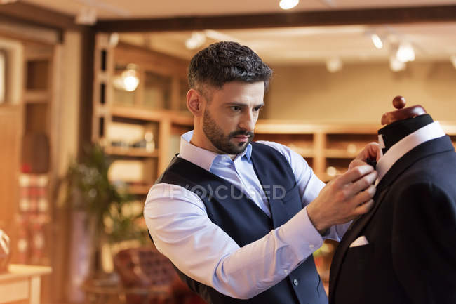 Tailor adjusting tie on dressmakers model in menswear shop — Stock Photo