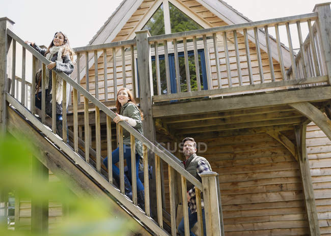 Friends climbing staircase outside wooden cabin — Stock Photo