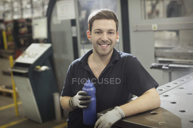 Portrait smiling worker with water bottle in steel factory — Stock Photo