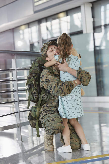 Filha cumprimentando abraçando soldado mãe no aeroporto — Fotografia de Stock