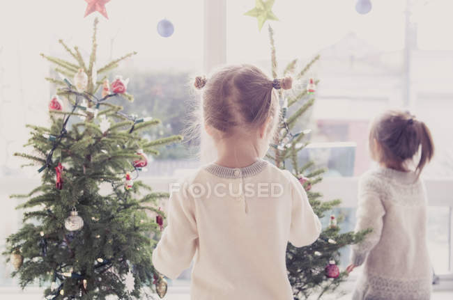 Niñas decorando pequeños árboles de Navidad - foto de stock