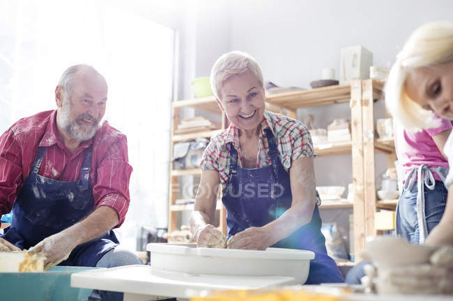 Улыбающаяся пожилая пара, использующая гончарные колеса в студии — стоковое фото