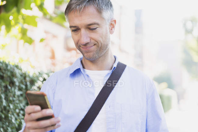 Empresario de mensajes de texto con el teléfono celular al aire libre - foto de stock