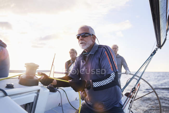 Retired man sailing holding rigging on sailboat — Stock Photo