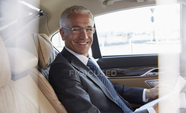 Портрет улыбающегося бизнесмена, сидящего на заднем сиденье городской машины — стоковое фото