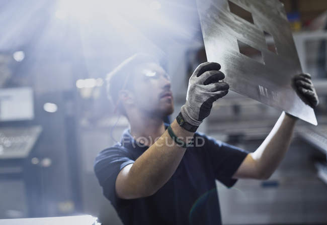 Worker examining piece in steel factory — Stock Photo